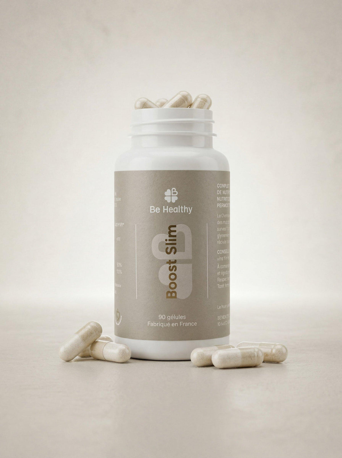 Flacon blanc de complément alimentaire en gélules Boost Slim à étiquette beige, gélules beiges au sol près de l&
