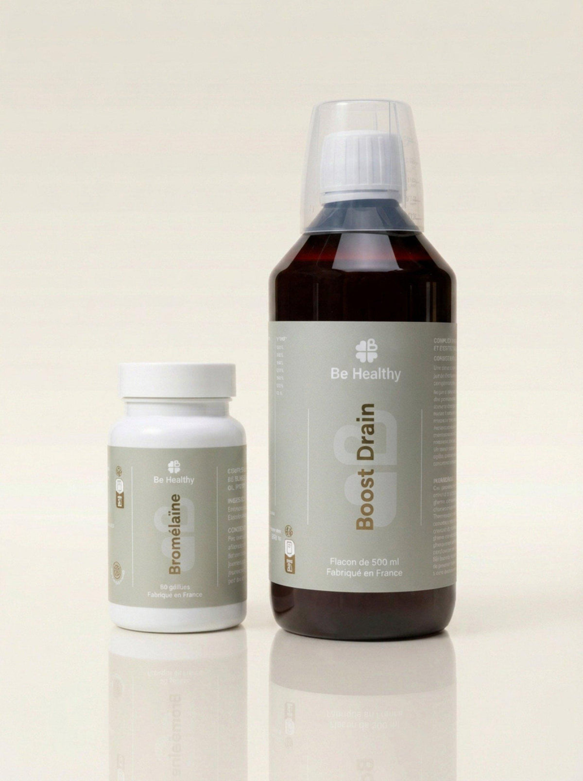 Pot blanc de Bromélaïne et grand flacon brun Boost Drain avec bouchon doseur sur fond crème, Protocole Détox Post-Op Be Healthy